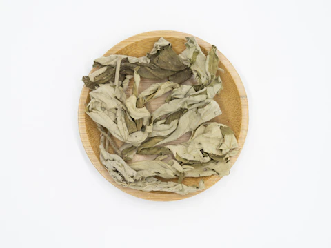 Soursop leaves freshly picked, laid out on a woven mat.