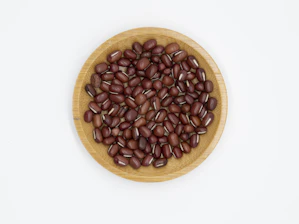 Close-up of fresh soybeans spilling from a rustic wooden bowl on a soft white cloth.