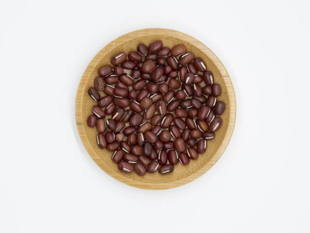 Close-up of fresh soybeans spilling from a rustic wooden bowl on a soft white cloth.