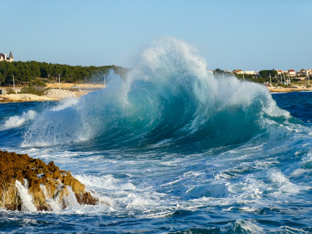 a large wave crashing into a rocky shore