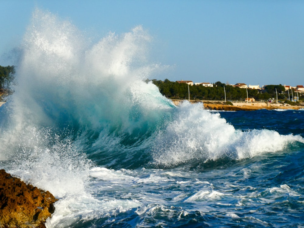 a large wave crashing into a rocky shore