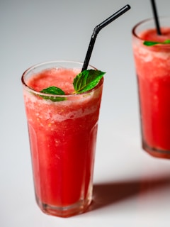 two glasses of watermelon drink with a black straw