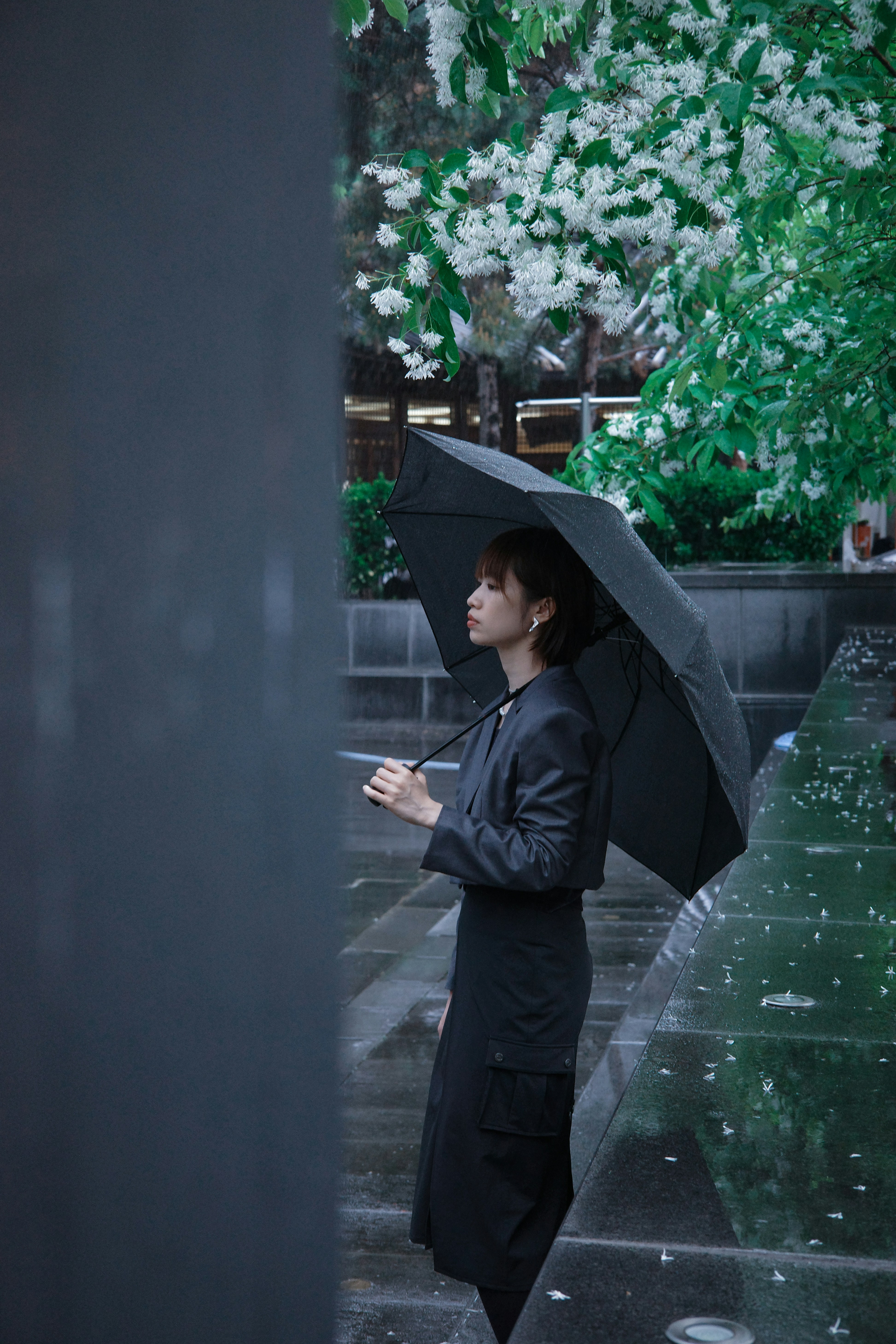 Eine Frau, die im Regen steht und einen Regenschirm hält