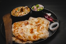 a black plate topped with food next to a bowl of salad