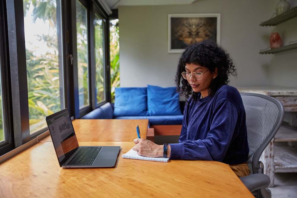 a woman sitting at a table with a laptop