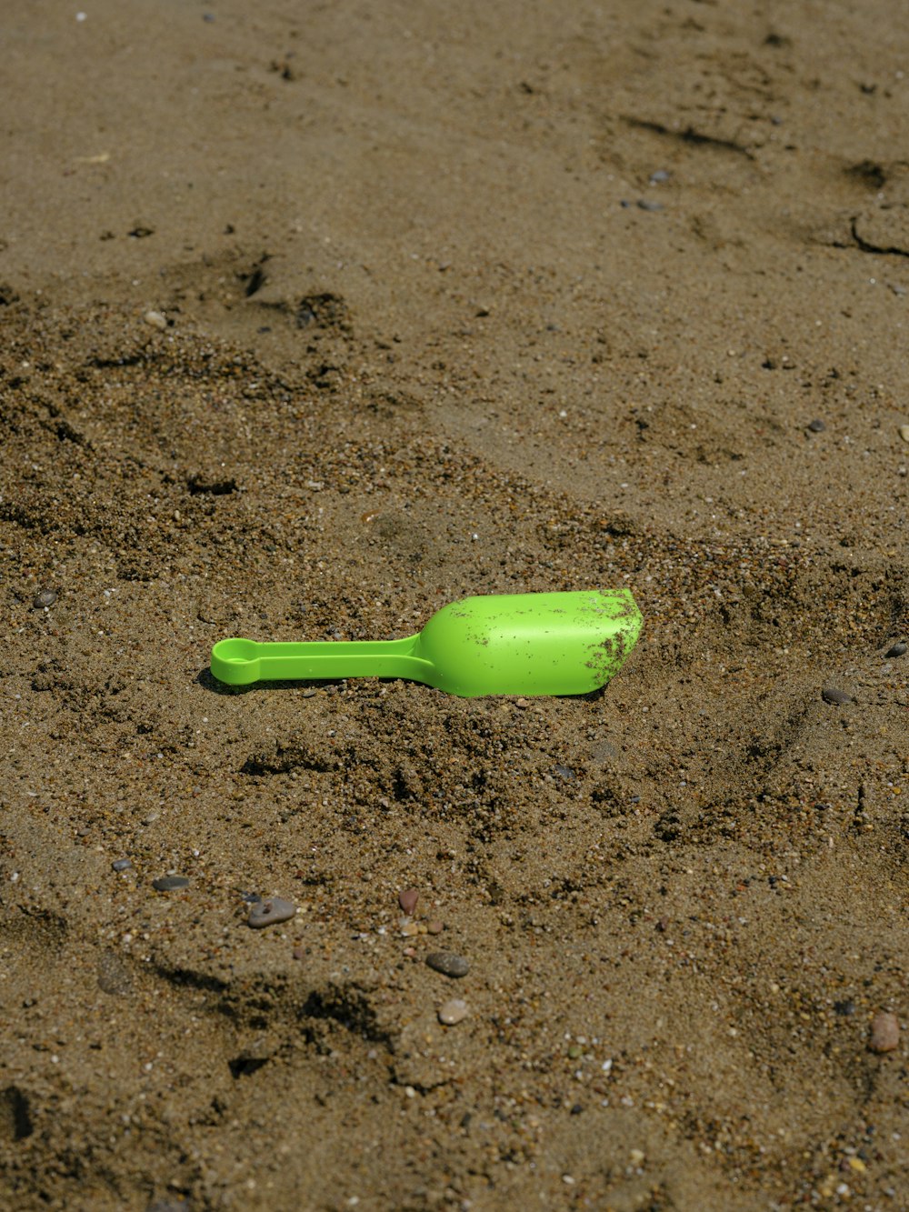a green plastic bottle laying in the sand