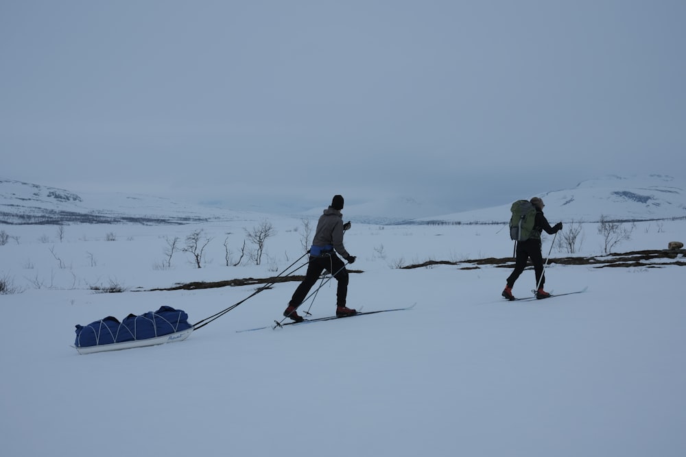 a couple of people walking across a snow covered field