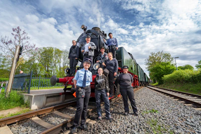 A group of railway employees celebrating a hard-won football tournament victory under clear blue skies