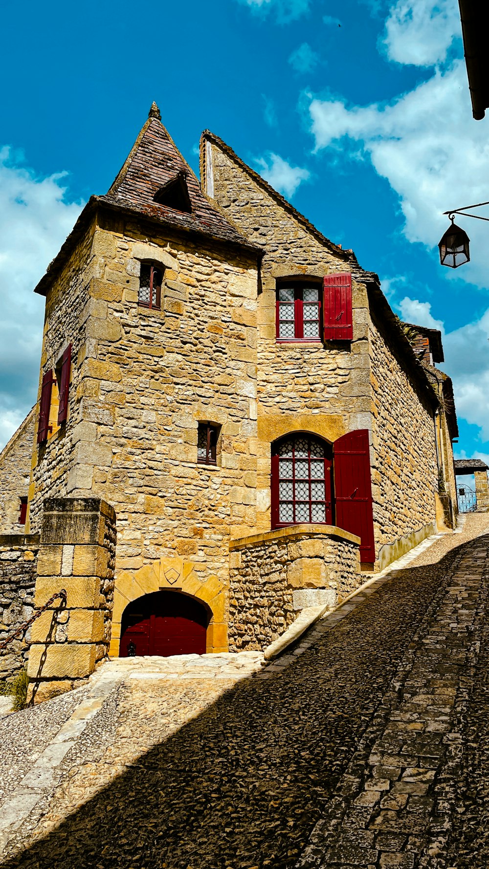 a stone building with red shutters and a red door