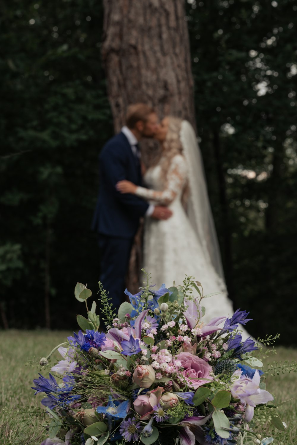 a bride and groom standing in front of a tree