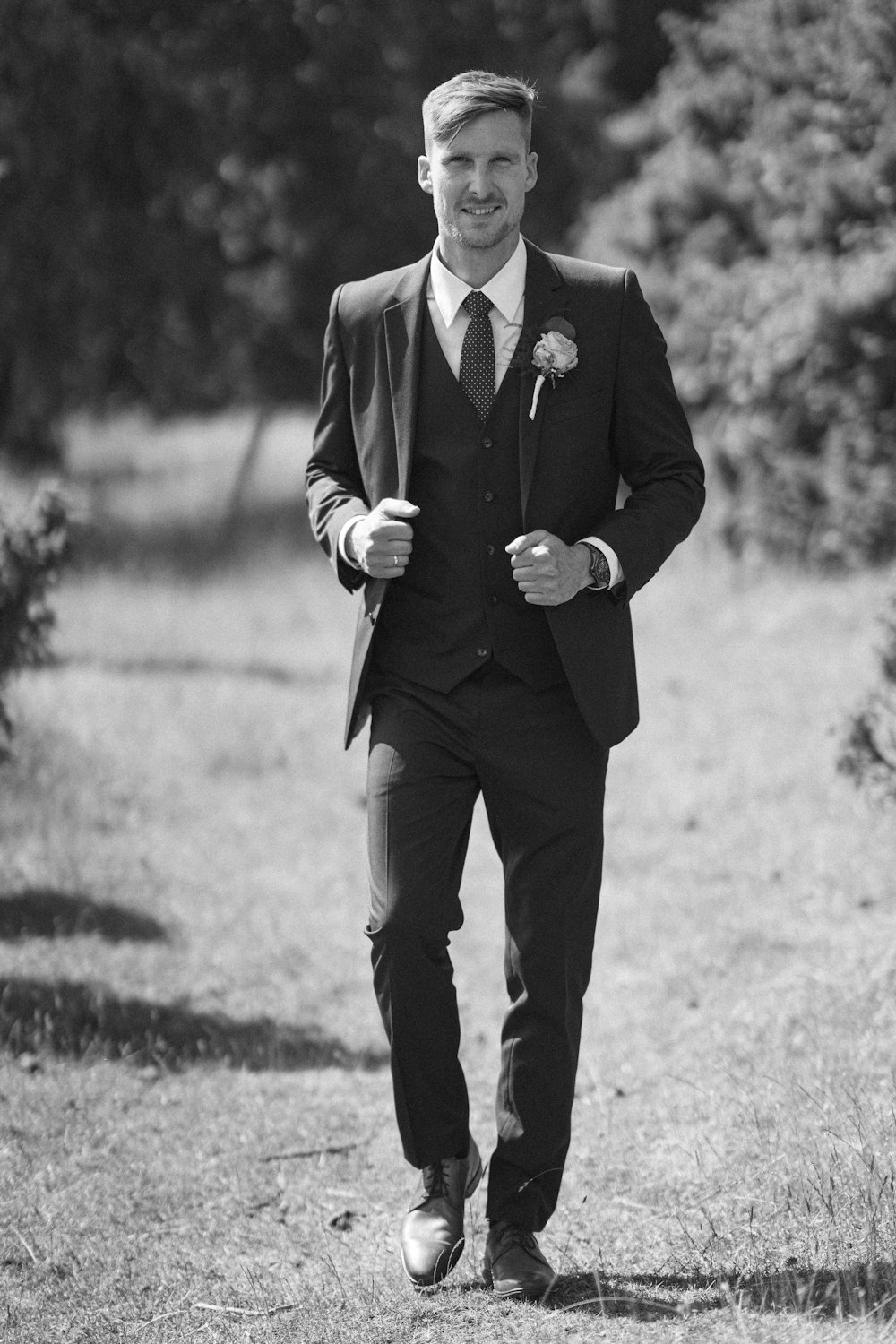 a man in a suit and tie walking in a field