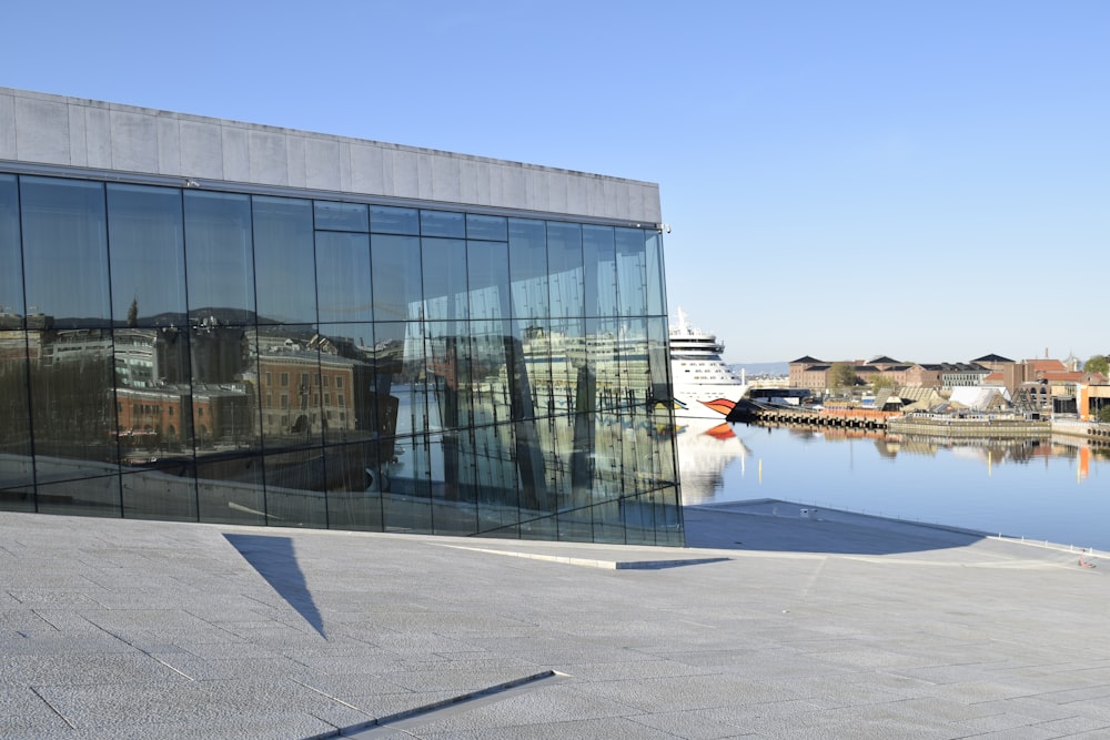 a large glass building with a reflection of a boat in it