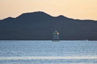 Sleek minimalist lighthouse shining over a calm sea at dawn.