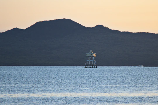 Sleek minimalist lighthouse shining over a calm sea at dawn.