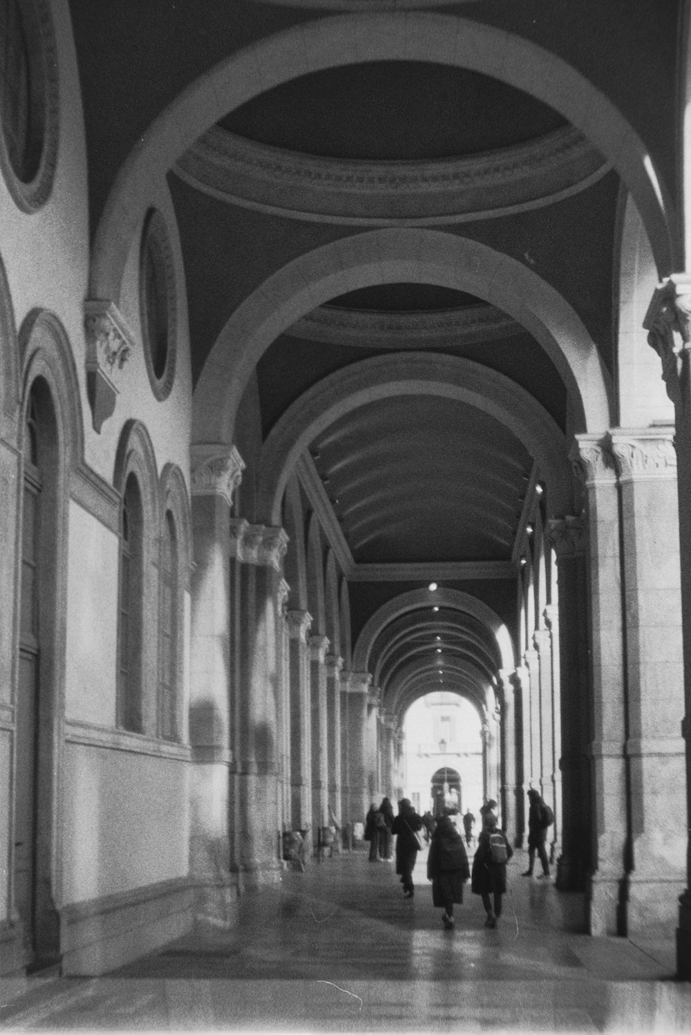 a black and white photo of people walking down a hallway
