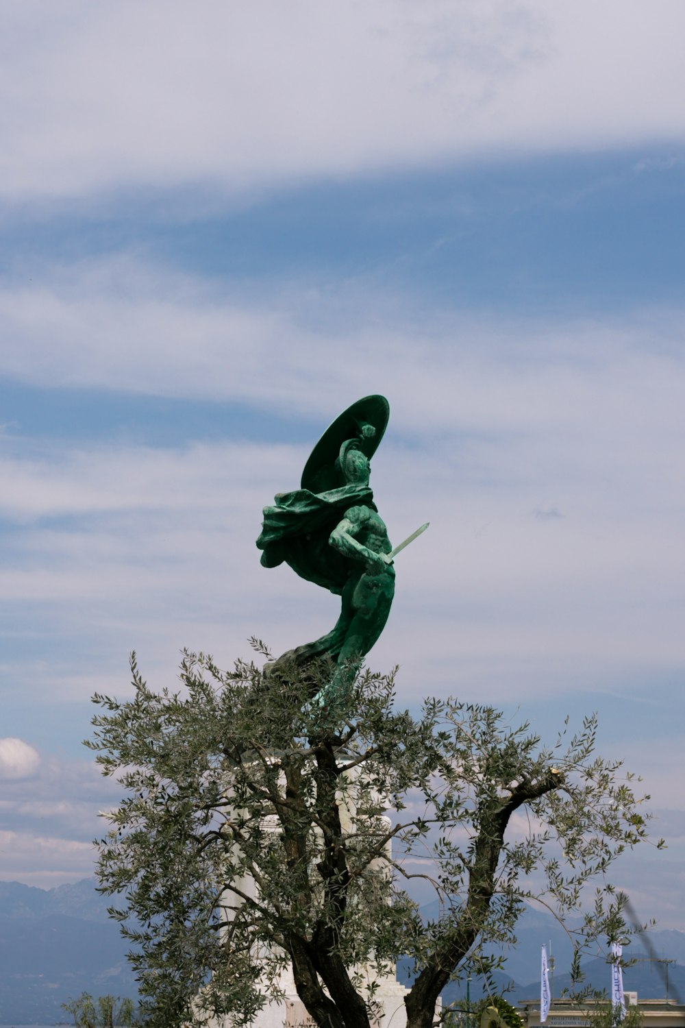 a statue of a man holding a sword on top of a tree