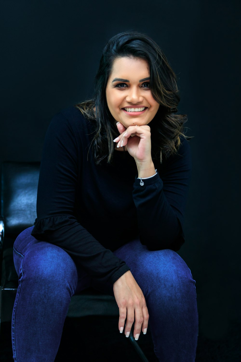 a woman sitting in a chair with her hand on her chin