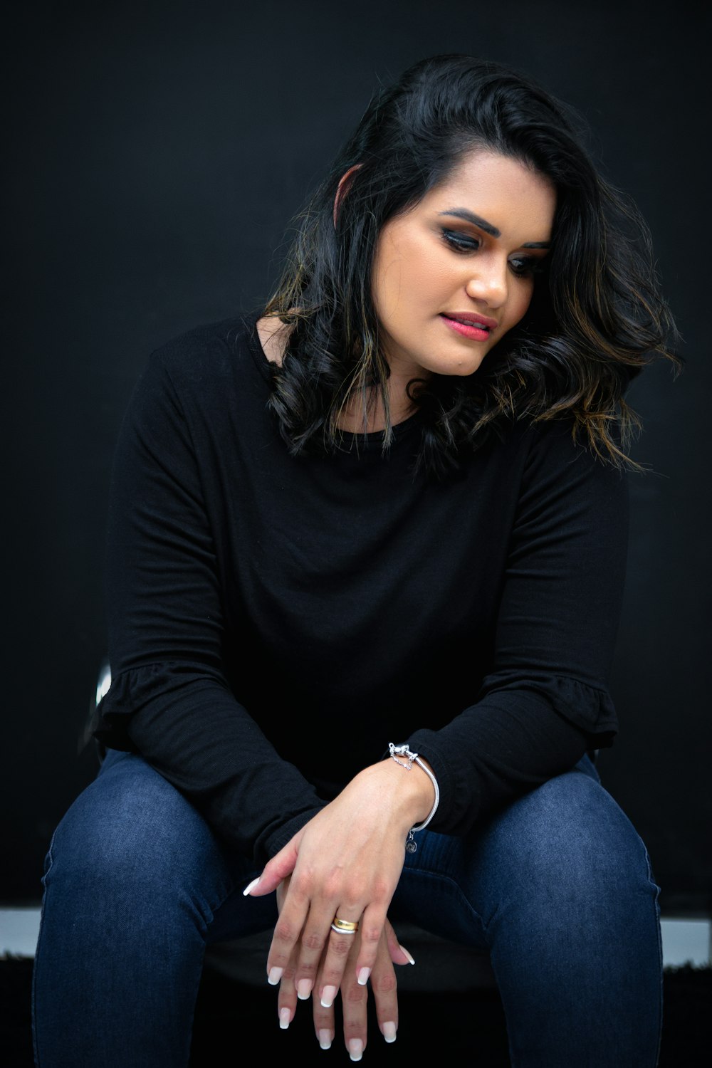 a woman sitting on a chair with her hands on her knees