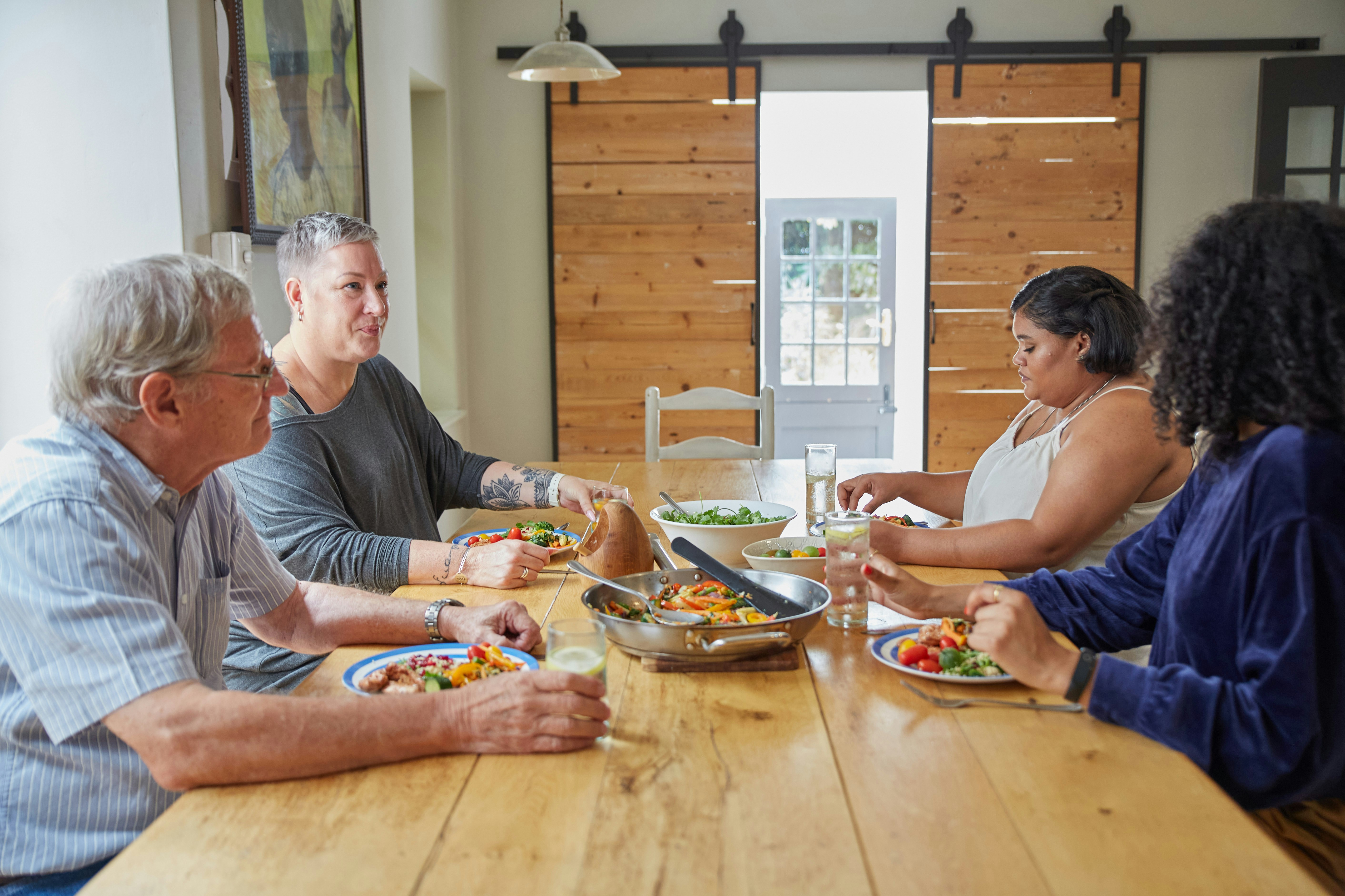 Guest enjoying home-cooked traditional Garhwali meal with host family around wooden dining table