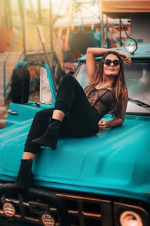 a woman sitting on the hood of a blue truck