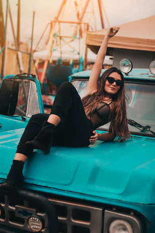 a woman sitting on the hood of a blue truck