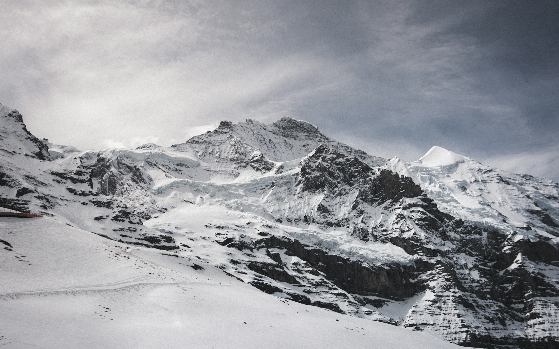 a mountain covered in snow under a cloudy sky