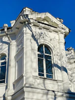 Elegant exterior view of a mansion with a pristine white facade against a bright blue sky.