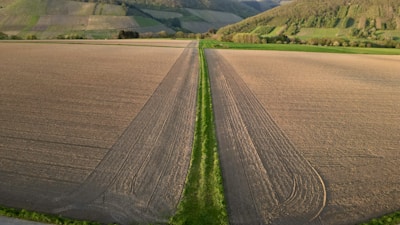 Aerial view of a vast green agricultural field with a farmhouse.