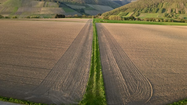 Wide aerial view of expansive agricultural fields under clear sky.