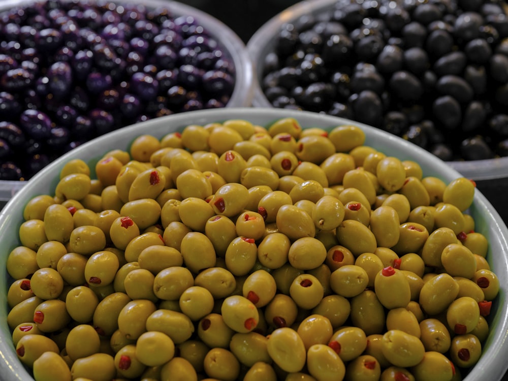 a bowl of olives with other olives in the background