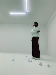 A calm, focused individual reflecting thoughtfully in a minimalist room.