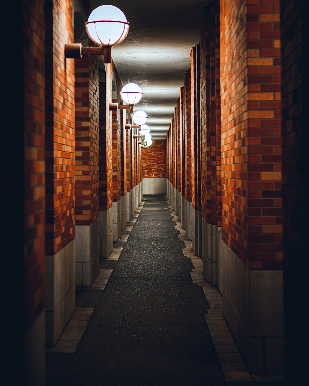 a long hallway between two buildings with red brick walls