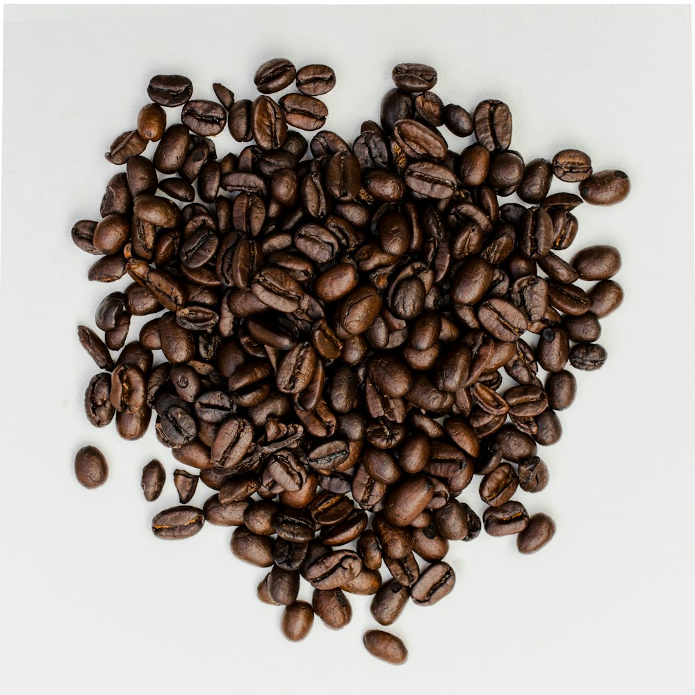 a pile of coffee beans on a white surface