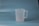 A translucent plastic measuring jug with a handle, placed against a plain blue background.