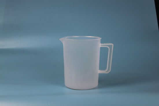 A translucent plastic measuring jug with a handle, placed against a plain blue background.