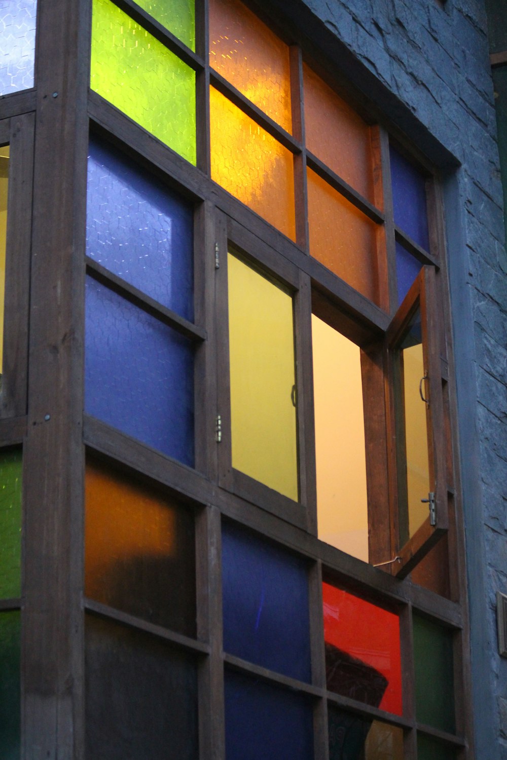 a multicolored window with a brick building in the background