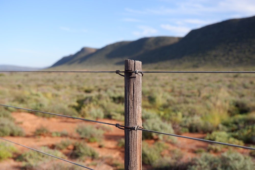 a wire fence with a mountain in the background