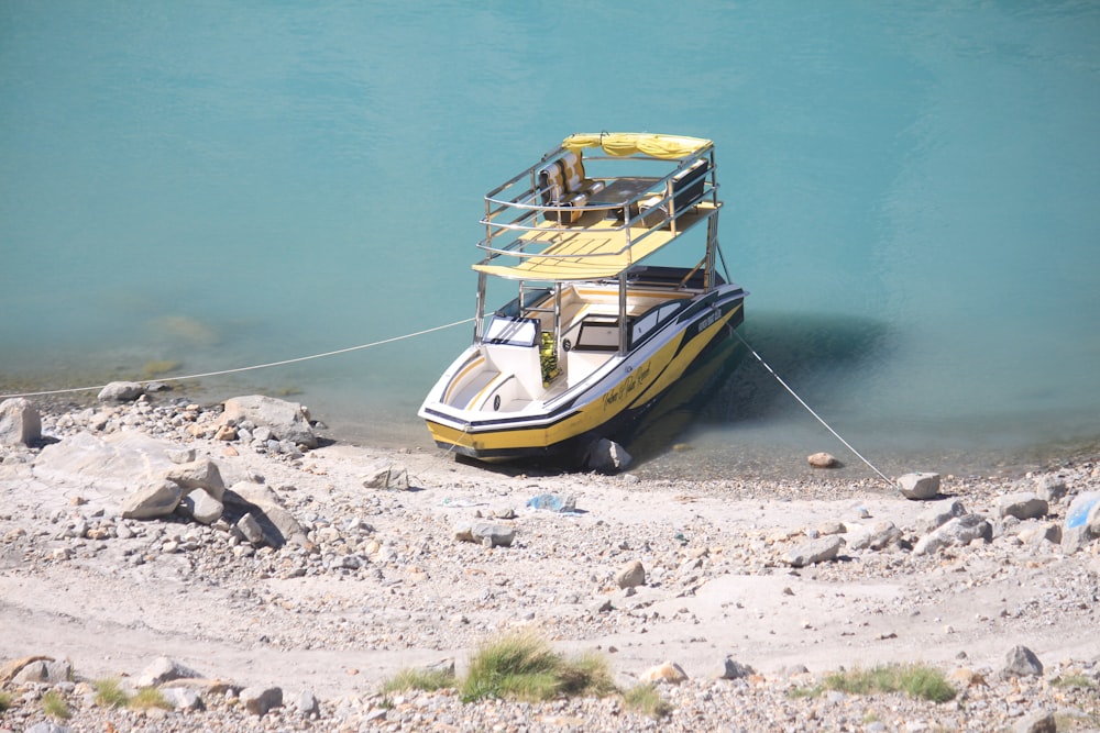 a yellow and black boat tied to the shore
