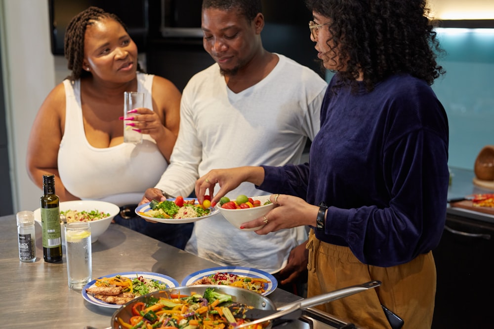 a group of people standing around a table with plates of food