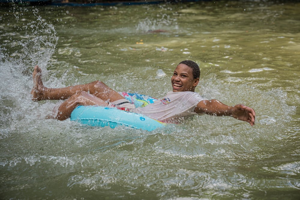 a woman riding a boogie board on top of a body of water