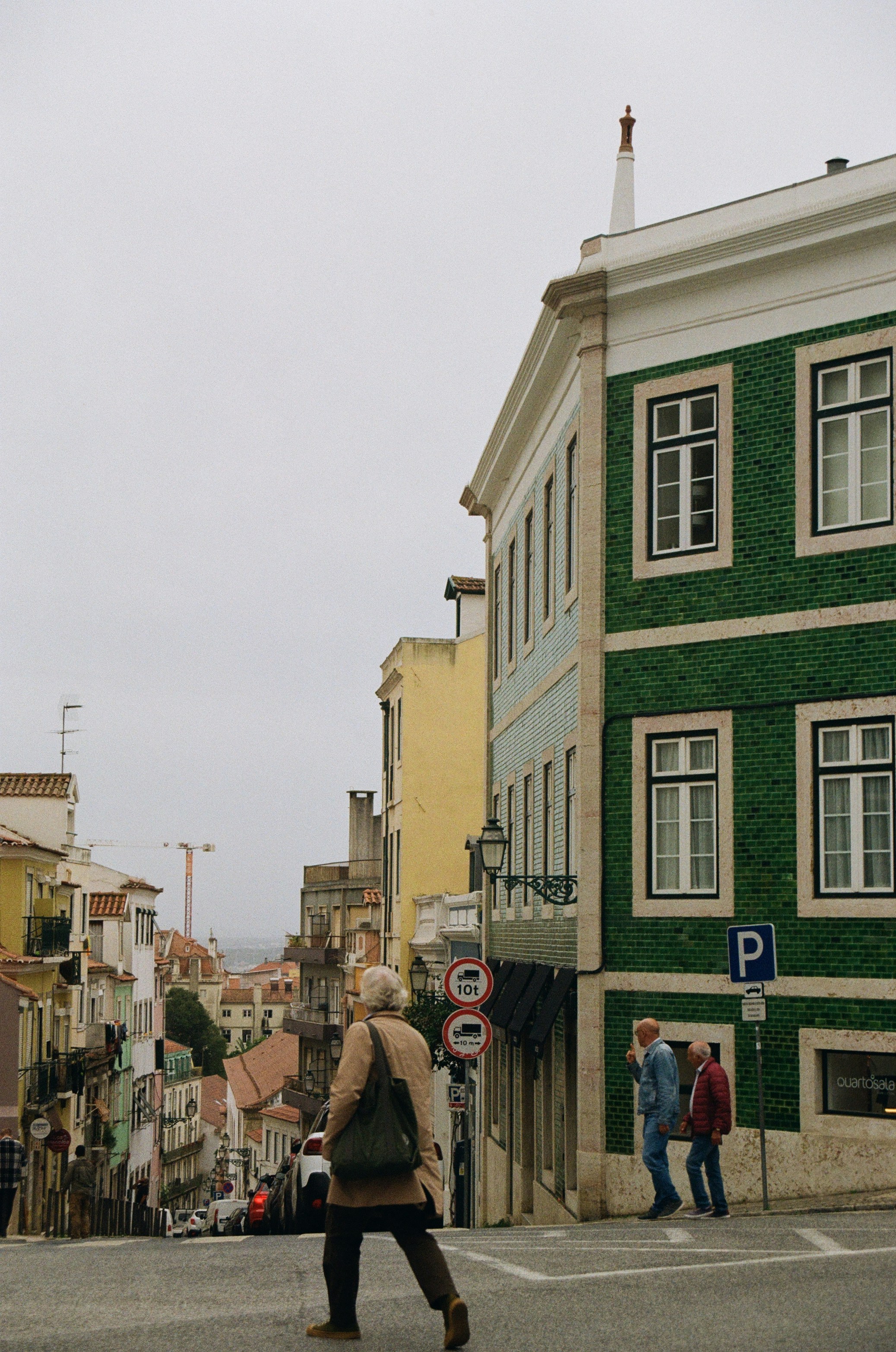 a man walking across a street next to a tall green building