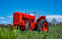 A vibrant photo of a farmer inspecting a shiny new tractor on a bright day.