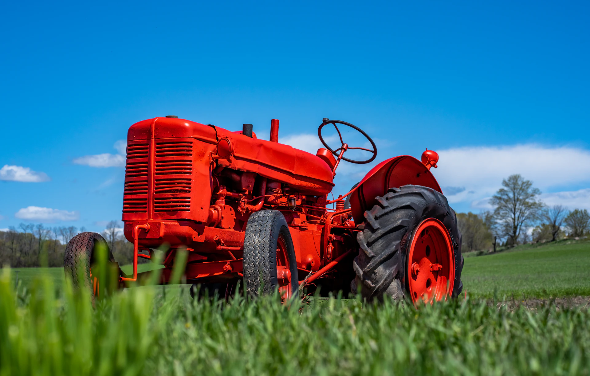 Red tractor parked on the grass at a vintage machinery show