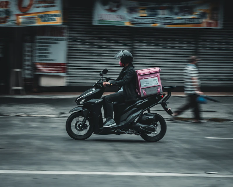 Repartidor en moto recorriendo una calle de comercios