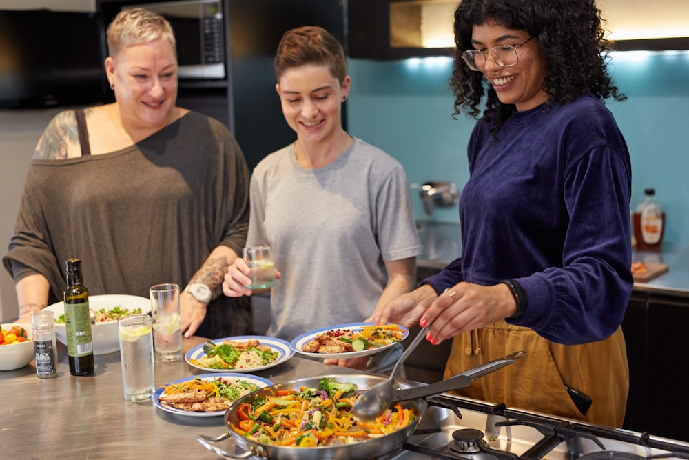 a group of people standing around a table filled with food