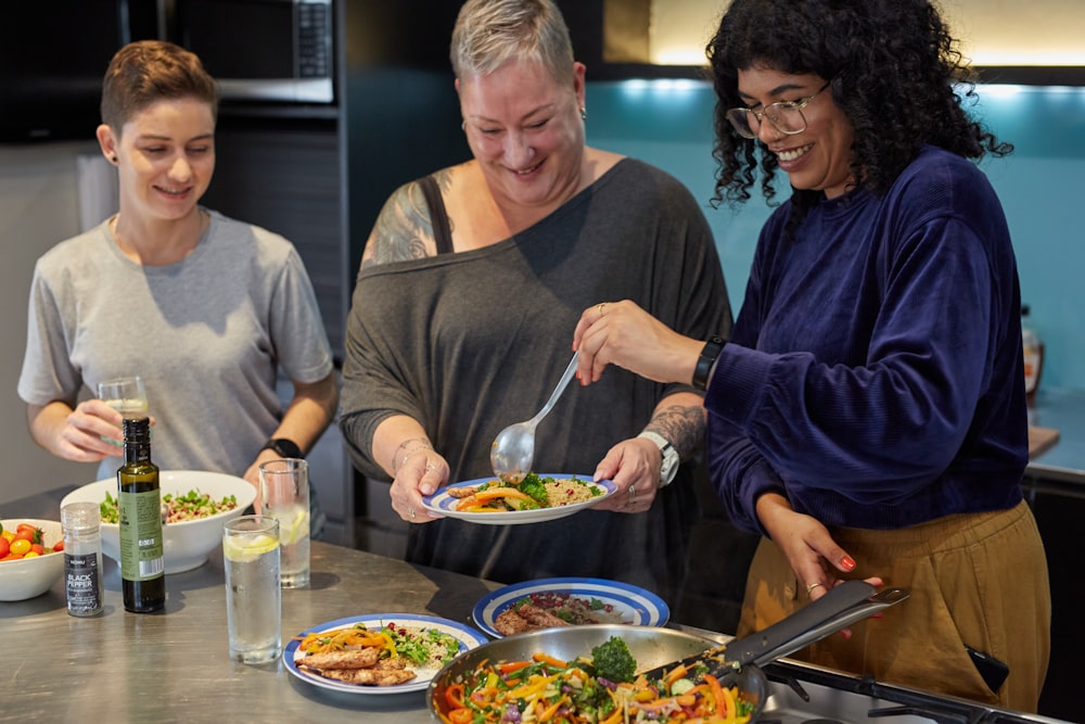 a group of people standing around a table with plates of food