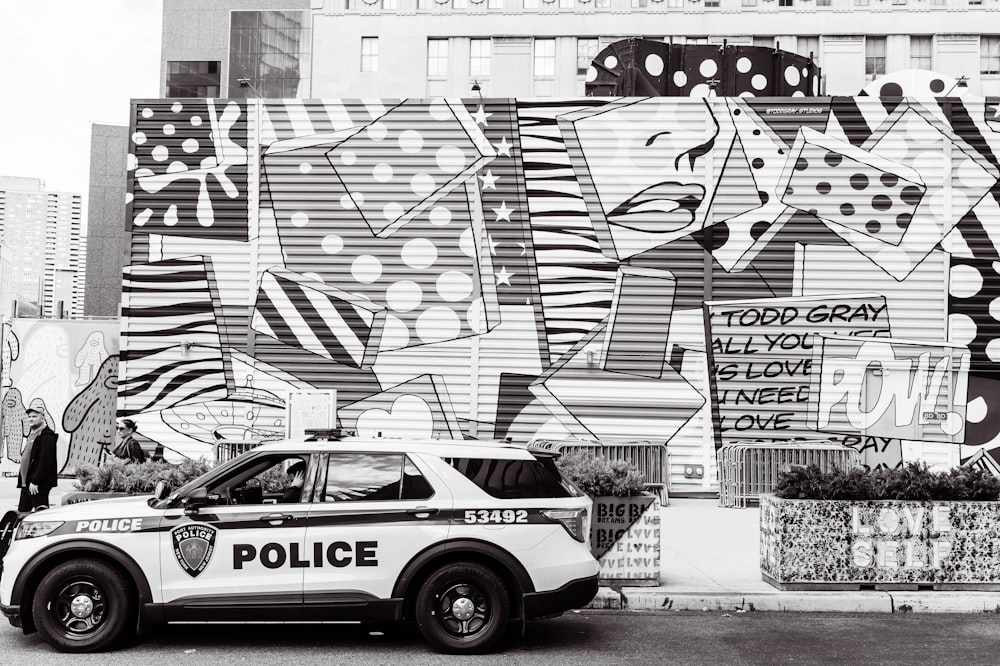 a police car parked in front of a wall covered in graffiti
