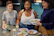 Residents sharing a meal together in a cozy kitchen, smiling and relaxed.