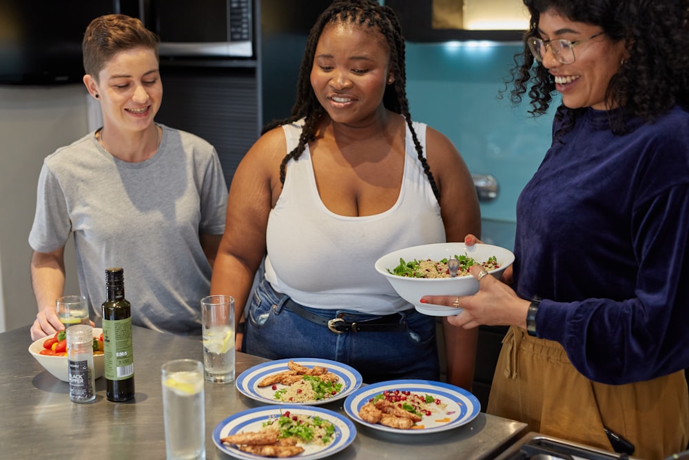 a group of women standing around a table with plates of food