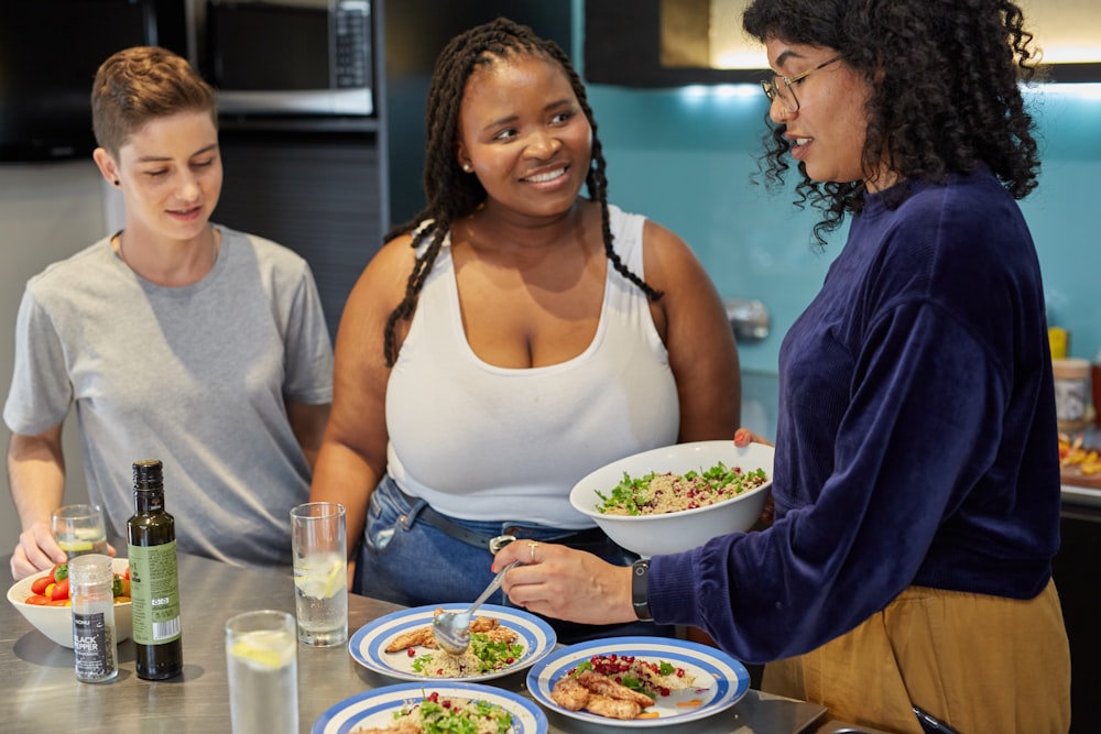 a group of people standing around a table with plates of food